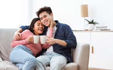 Naklejka na ściany i meble Loving Asian Husband And Wife Drinking Morning Coffee At Home