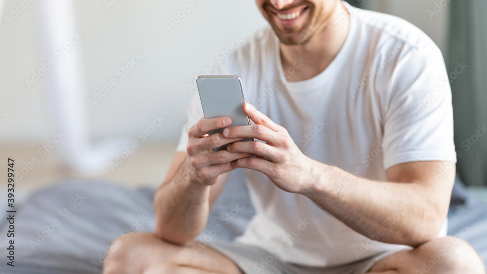 Poster unrecognizable guy using phone with mobile application in bedroom, cropped