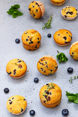 Fresh homemade delicious blueberry muffins decorated with thyme, fresh berries and mint on grey background. Top view.