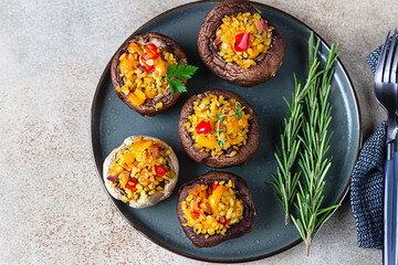 Baked stuffed portobello mushrooms with bulgur pilaf and chopped vegetables. Delicious and nutritious vegetarian dish. Top view.