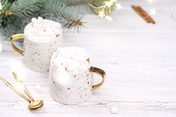 White cup of cappuccino or cocoa with christmas tree on the buckground of gold bokeh, New Year hot drink