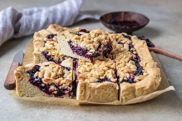 Homemade shortcrust berries jam pie on baking paper, light background. Crumble cake.