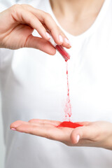 Closeup of manicure master pours red pigment nail powder from tube on her palm