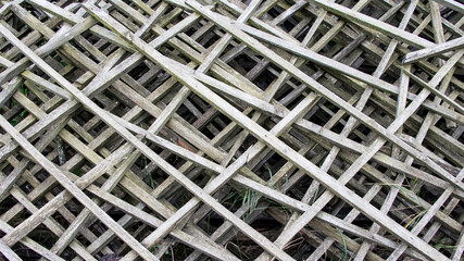 Old gray diagonal wooden grate. Old fence made of wooden lattices. Background