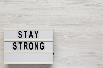 'Stay strong' on a lightbox on a white wooden background, top view. Flat lay, overhead, from above. Copy space.