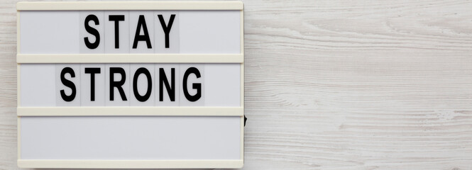 'Stay strong' on a lightbox on a white wooden surface, top view. Flat lay, overhead, from above. Space for text.