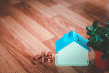 Obraz na płótnie Canvas savings concept, A house model, and a pile of coins on a wooden board