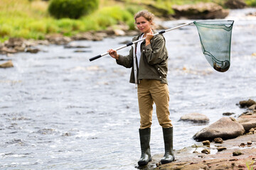 A girl on a fishing trip holds a landing net with a fish