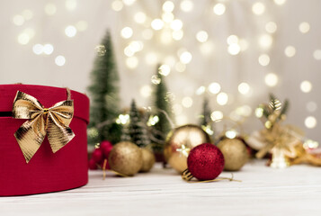Fototapeta na wymiar red round gift box with a Golden bow on the background of Christmas bokeh.