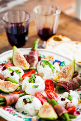 Close up of a traditional Italian dish with mozzarella, tomatoes, prosciutto ham and fresh basil. Selective focus - shallow depth of field.