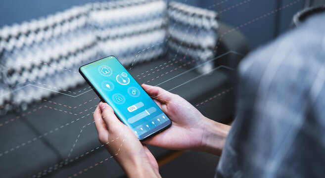 Smart home modern technology Asian girl sitting living room using smartphone mobile controlling remote system navigating adjusting functions light temperature and security setting, UI screen display