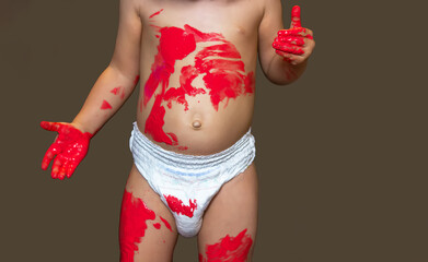 A cute little Caucasian girl in a diaper cheerfully draws on her body with gouache. The happy child...
