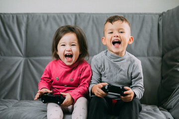 Brother and sister with a gamepad in their hands playing games shouting having fun