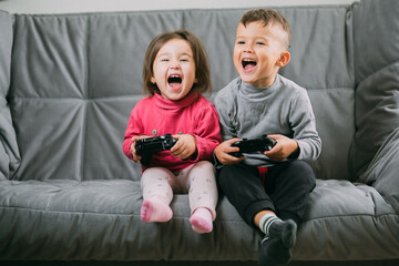 Brother and sister with a gamepad in their hands playing games shouting having fun