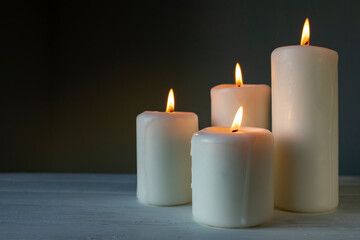 Fototapeta na wymiar Large burning candles on a dark background.