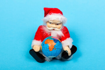 Merry Christmas and Happy New Year! Toy santa claus holding a globe