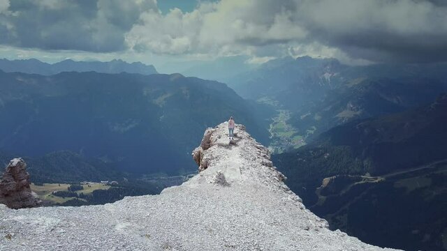 Freedom concept: Flying over woman raising hands on the top of Piz Boe mountain in Dolomites.