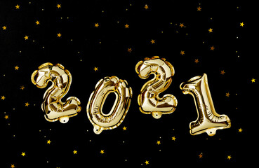 Happy New year 2021 celebration. Gold foil balloons numeral 2021 and gold confetti on black background. Happy New year composition.