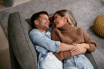 Young loving couple relaxing on sofa together. Happy couple enjoying at home.