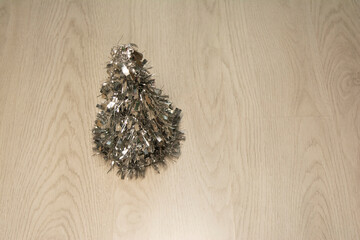 toy in the form of a Christmas tree made of silver tinsel, on a light gray laminate. horizontal. Christmas. New Year. Minimalistic. indoor. holiday symbol. copy space. interior. decoration. design.