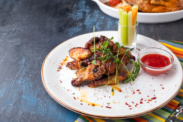 BBQ chicken wings served with vegetables and  ketchup on a plate. Copy space