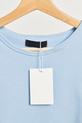T-shirt with a blank tag mockup on a wooden hanger - obrazy, fototapety, plakaty