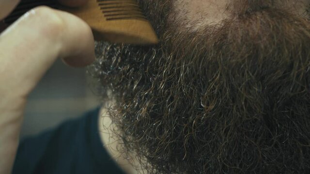 Close up footage of bearded man brushing his beard