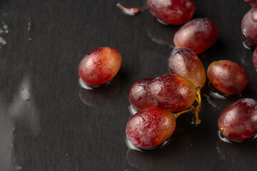 Aerial view of wet red grapes on wet slate, selective focus, with back light, horizontal, with copy space