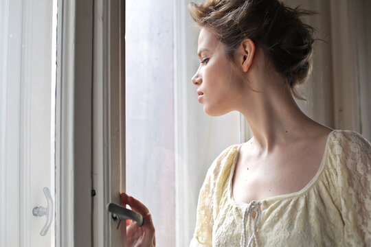 young woman looks out of the window