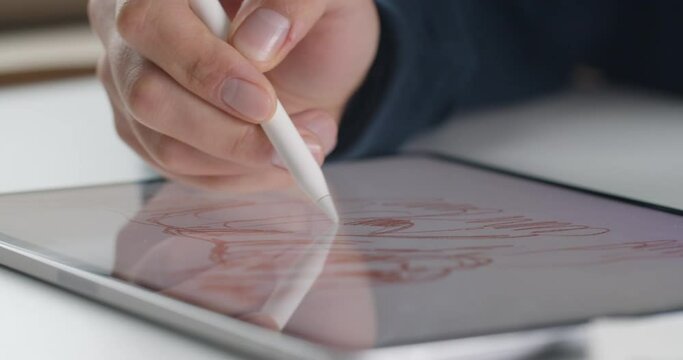 Close up view of person hand drawing digital scetch picture by stylus at display of notepad. Concept of creativity