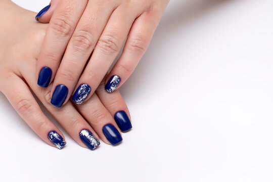 Dark blue manicure with silver matte foil under a business card on a white background on long square nails.