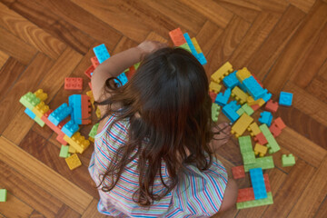 girl playing with blocks on the wooden floor in her room