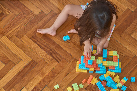 girl playing with blocks on the wooden floor in her room
