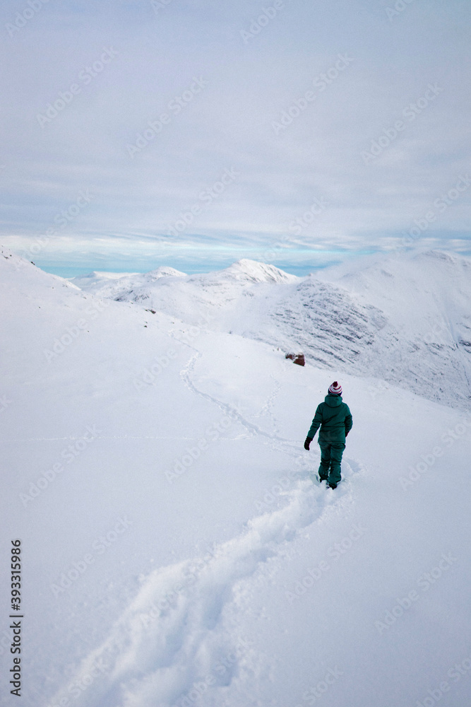 Wall mural Woman trekking on a snowy mountain