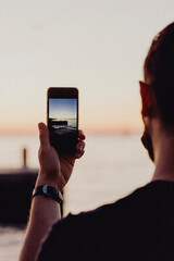 Man capturing a picture of the lake at dusk