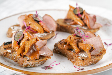 Traditional Scandinavian open sandwich with chanterelle mushrooms, cream cheese and ham on white plate