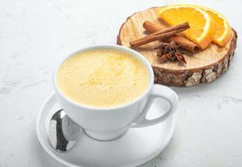 Cappuccino coffee with orange flavor and cinnamon in a white mug on a white background.