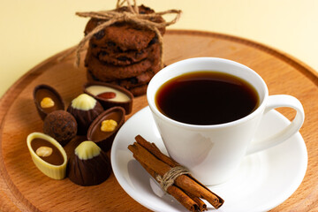 Cup of coffee and chocolates on a wooden tray.