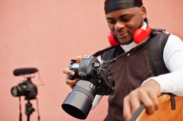 Young professional african american videographer holding professional camera with pro equipment. Afro cameraman wearing black duraq making a videos.