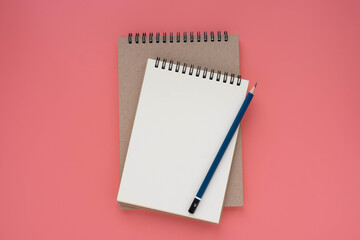 Top view above of open white blank spiral notebook and pencil isolated on pink background for design a mockup. Education and business concept. flat lay