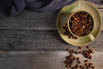 Top view above of Black coffee seed for morning menu in brown ceramic cup with coffee beans roasted on old wooden table background. Flat lay with copy space.
