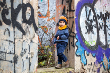 Fototapeta na wymiar Child, posing in an old ruin building, sprayed with graffiti