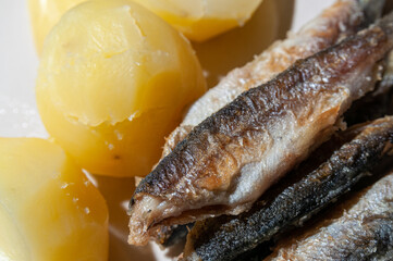 Top view of small fried fish and boiled potatoes on a plate