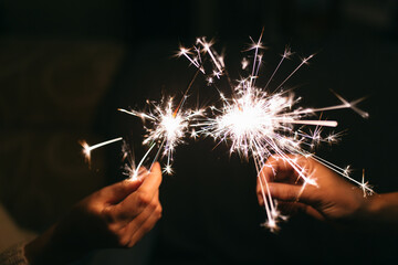Burning New Year sparkler. Bengal light scattering into small sparkles. Celebrating christmas and new year 2021
