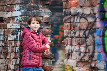 Child, posing in an old ruin building, sprayed with graffiti