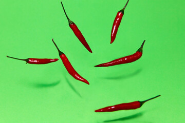 Levitation background. Red hot pepper soaring in the air. Red hot pepper falling on a green surface.