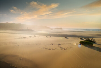 couple with their hand up in the air on beautiful white sand beach, dreamers written down on the sand, bird eye view