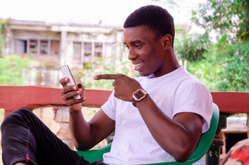 a young handsome african man smiling as he operates his phone