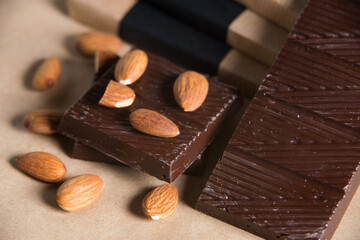 Close-up of homemade chocolate bar with almond on craft paper background