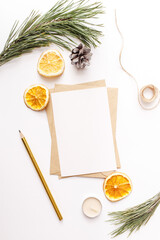 Christmas, New year composition. Paper blank mock up, fir tree branches, pine cone, dried oranges, cinnamon sticks, gold pen candles on white background. Flat lay, top view, copy space